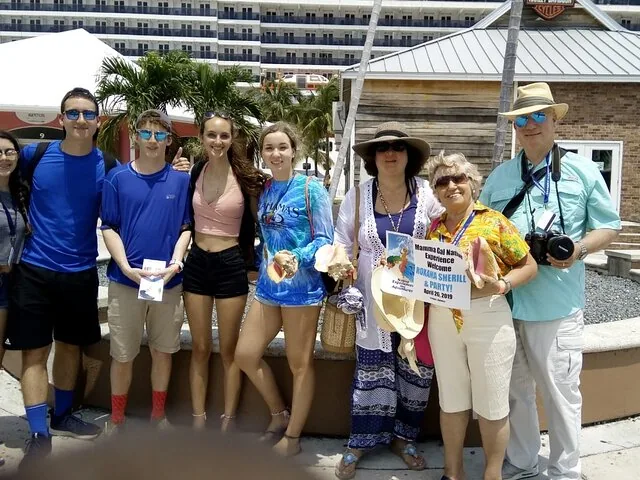 Group of tourists posing for a photo near a cruise ship.
