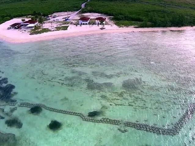 Aerial view of a coastal resort building and clear water.